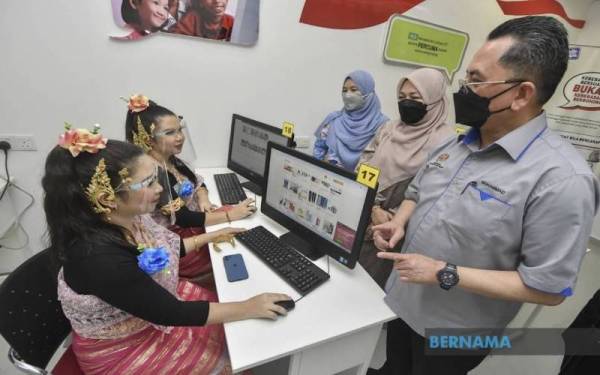 Mohammad Mentek (kanan) beramah mesra dengan pasangan kembar Waleen Chua Rui Wen (kiri) dan Wareen Chua Rui Yin (dua, kiri) sewaktu lawatannya ke Pusat Ekonomi Digital (PEDI) Kampung Terbak pada Ahad. - Foto Bernama