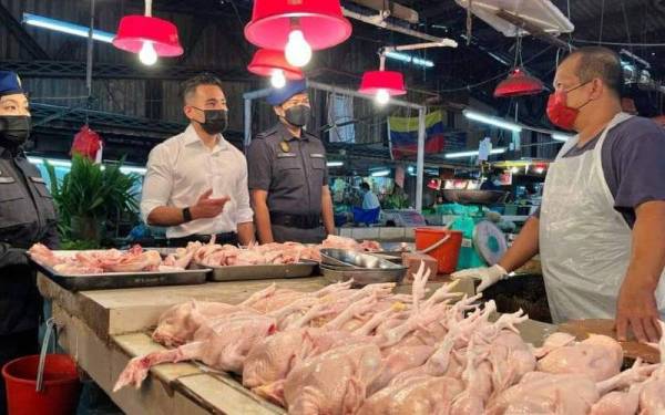 Shahril (kiri) bersama pasukan KPDNHEP Wilayah Persekutuan Kuala Lumpur bertanya peniaga mengenai harga ayam ketika melakukan pemantauan di Pasar Keramat pada Isnin.