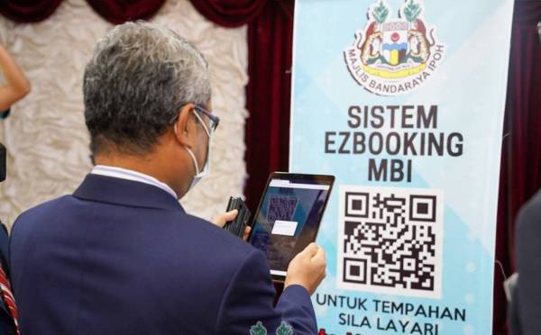 Rumaizi mengimbas kod QR untuk simbolik melancarkan sistem EzBooking MBI. Foto: ihsan MBI