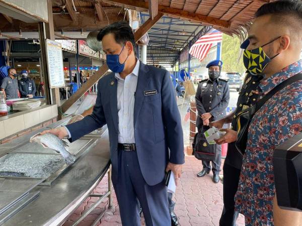 Pengarah KPDNHEP, Saharuddin Mohd Kia memeriksa salah seekor ikan siakap yang dijual di salah sebuah restoran di sekitar Kuala Terengganu, pada Selasa.