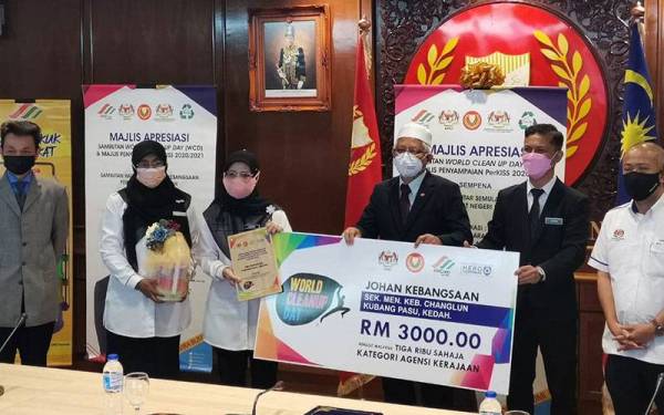 Dr Mohd Hayati (tiga, kanan) dan Nordin (dua, kanan) menyerahkan replika kemenangan kepada wakil Sekolah Menengah Kebangsaan (SMK) Changlun yang muncul johan kebangsaan World Clean Up Day (WCD), di Wisma Darul Aman.