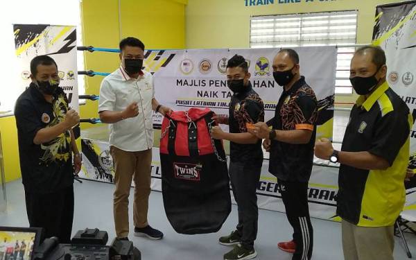 Mohd Iruan (dua dari kiri) menyerahkan peralatan tinju selepas menyempurnakan Majlis Penyerahan Naik Taraf Pusat Latihan Tinju Negeri Perak, di Pusat Latihan Tinju Negeri Perak, di Ipoh pada Khamis.