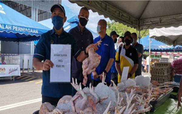 Yunus menunjukkan harga jualan ayam segar yang murah ketika melawat gerai di program Jualan #Keluarga Malaysia peringkat Perak di RTC Gopeng.