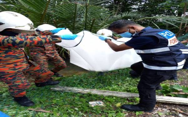 Anggota bomba dibantu polis mengangkat mayat kanak-kanak yang ditemukan dalam keadaan tidak sempurna di kawasan semak dalam sungai di Kampung Desa Makmur, Johor Bahru pada Sabtu.