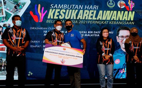 Ahmad Faizal (dua, kiri) menyampaikan Anugerah Khas Sukarelawan kepada Nermesh Singh A/L Gurbish Singh (tengah) pada Program Hari Kesukarelawanan Belia Malaysia 2021 (HKBM2021) di Pusat Konvensyen Casuarina Meru hari ini. -Foto Bernama