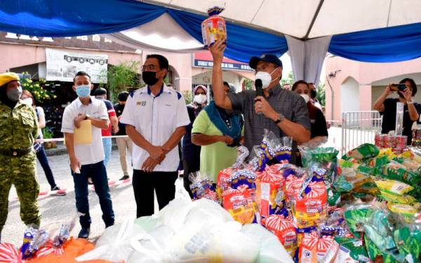 Hasnol Zam Zam (kanan) membuat lelongan jualan roti putih pada harga RM1 sebungkus pada Program Jualan Keluarga Malaysia (PJKM) di Alor Gajah pada Ahad. - Foto Bernama 