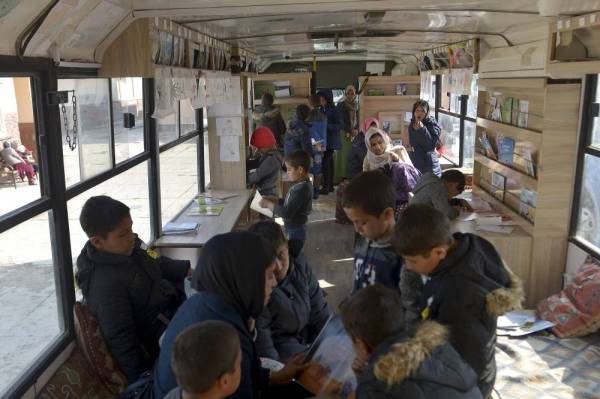 Children stand inside a mobile library which opened its doors for the first time since the Taliban's return to power, in Kabul on December 5, 2021. (Photo by AHMAD SAHEL ARMAN / AFP)