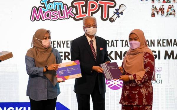 Ismail Sabri (tengah) menyerahkan surat tawaran sesi 2 2021/2022 Program Asasi Undang-Undang UiTM kepada Farah Syuhadah Zahari (kanan) ketika menghadiri Lawatan ke ruang pameran Jom Masuk IPT sempena program 100 Hari Aspirasi #KeluargaMalaysia di Pusat Konvensyen Kuala Lumpur hari ini. - Foto Bernama