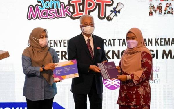 Ismail Sabri (tengah) menyerahkan surat tawaran sesi 2 2021/2022 Program Asasi Undang-Undang UiTM kepada Farah Syuhadah Zahari (kanan) di Pusat Konvensyen Kuala Lumpur pada Jumaat. - Foto Bernama