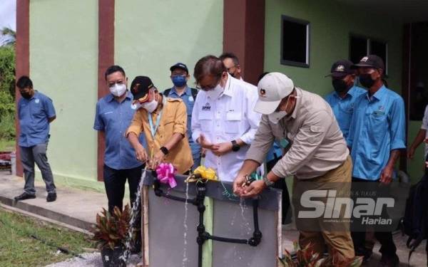 Abang Johari (tengah) bersama penyandang DUN Gedong, Datuk Mohd Naroden Majais (kiri) melakukan simbolik perasmian Bekalan Air Luar Bandar di Kampung Punggor, Gedong pada Khamis.