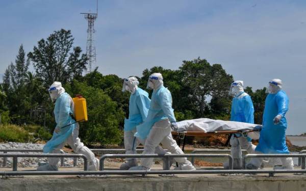 Kakitangan Kementerian Kesihatan Malaysia mengusung satu mayat lelaki yang dipercayai mangsa bot karam Tanjung Balau di Kompleks LKIM Pengerang dekat Tanjung Batu Layar hari ini. -Foto Bernama