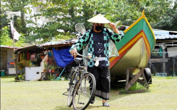 Gelagat seorang lelaki, Nikezuandi Idris, 41 yang mengenakan pakaian watak manga atau animasi Jepun popular 'Demon Slayer' menunjuk jarinya yang telah dicalit dakwat selepas mengundi. - Foto Bernama