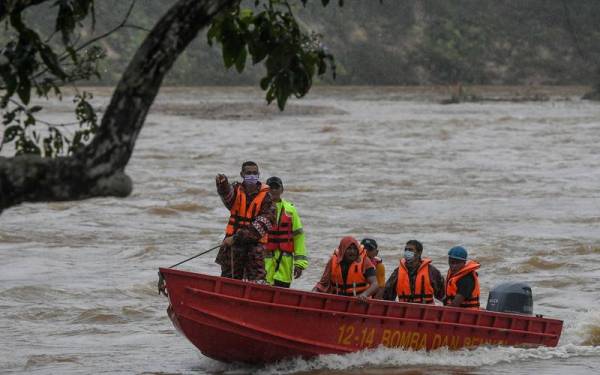 Anggota JBPM menyelamatkan mangsa banjir dengan menggunakan bot untuk dipindahkan ke kawasan lebih selamat berikutan hujan lebat sejak semalam ketika tinjauan di Kampung Shukor, Dungun hari ini. - Foto Bernama