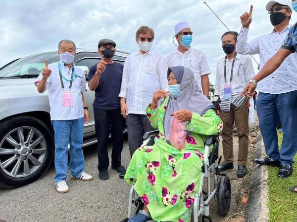 Abang Johari (tiga dari kiri) dan Naroden (kiri) bergambar bersama-sama pengundi di pekarangan pusat mengundi SK Abang Kadir Gedong, pada Khamis.