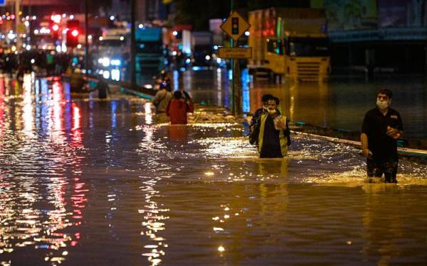 Beberapa orang awam dilihat meredah banjir kilat yang terjadi akibat limpahan air dari Sungai Damansara dan mengakibatkan jalan di Batu 3 Lebuhraya Persekutuan ditenggelami air dan tidak boleh dilalui oleh kenderaan. - Foto Bernama