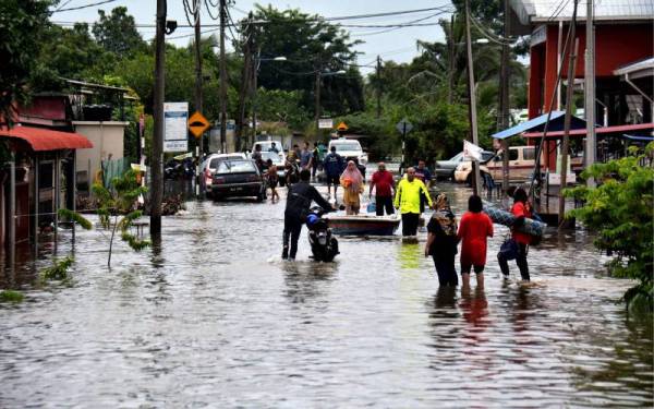 Penduduk Kampung Belukar meninggalkan kediaman masing-masing untuk ke pusat pemindahan sementara setelah kampung itu dinaiki air berikutan limpahan air sungai Belat hari ini. - Foto Bernama