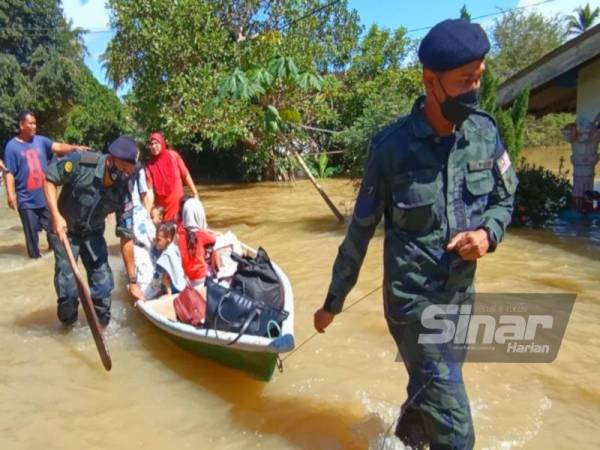 Azhari (kiri) bersama anggotanya membantu penduduk di Kampung Tersang berpindah ke kawasan selamat selepas kampung tersebut berubah menjadi 'pulau' apabila air Sungai Golok melimpah sejak malam Ahad.