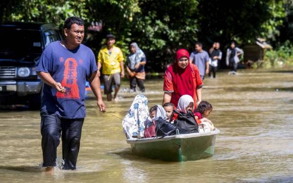 Penduduk setempat, Khairul Anuar Muhamad, 37, (kiri) menarik sampan bersama isteri dan anaknya untuk berpindah ke rumah saudara mereka setelah rumah mereka ditenggelami banjir ketika tinjauan di Kampung Tersang Rantau Panjang hari ini. - Foto Bernama