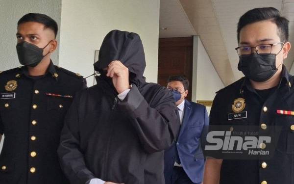 Anggota SPRM membawa Kuang Ming (tengah) ke Mahkamah Sesyen Kuala Lumpur pada Isnin bagi menghadapi pertuduhan kes menerima rasuah RM21,940 berhubung penjualan 21 kereta.