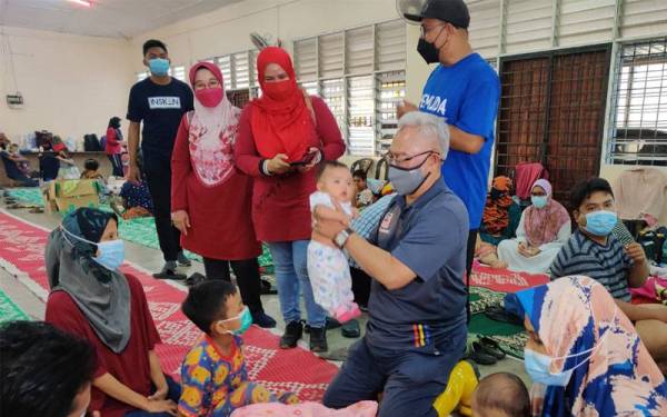 Noh (dua dari kanan) beramah mesra bersama mangsa banjir di Dewan Orang Ramai Kampung Bestari Jaya di sini pada Isnin.