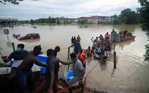 Orang ramai bersama anggota Jabatan Bomba dan Penyelamat Malaysia bekerjasama untuk mengeluarkan mangsa banjir di sebuah taman perumahan di Bukit Kemuning- Foto Bernama