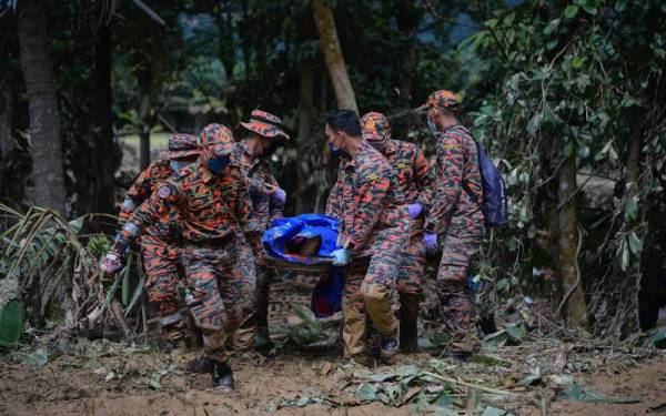 Anggota Jabatan Bomba dan Penyelamat Malaysia (JBPM) membawa keluar satu daripada tiga mayat mangsa banjir lumpur di Sungai Telemong pada Isnin.