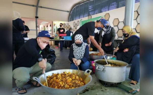 Mohamad Khairil (kiri) bersama-sama kakitangan PKPS menyiapkan makanan tengah hari kepada mangsa banjir sekitar Shah Alam.