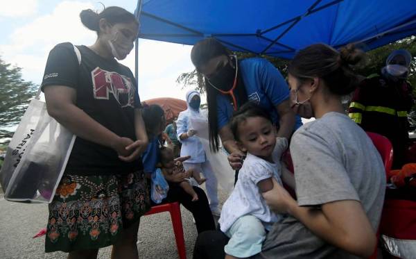 SHAH ALAM, Dec 21 - Medical personnel checking a sick child at Tamn Sri Muda, Shah Alam today amidst the flood recovery process. (Source: Bernama)