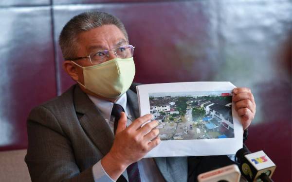 Dr Adham menunjukkan gambar keadaan banjir yang dirakam melalui dron pada sidang media selepas pelancaran produk teknologi hijau DeScale pada Selasa. - Foto Bernama 