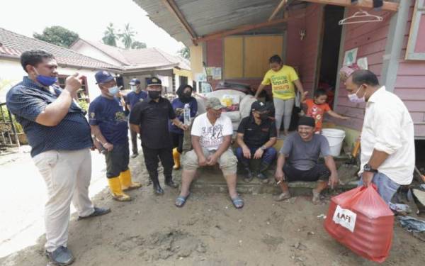 Ronald (tiga dari kanan) beramah mesra dengan mangsa-mangsa banjir dan menyerahkan bantuan.