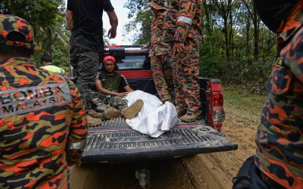 Seorang waris mangsa banjir lumpur menangis di samping jenazah ibunya selepas ditemukan oleh pasukan mencari dan menyelamat di Sungai Telemong, semalam. - Foto Bernama 