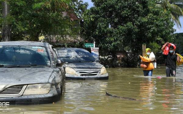 Flood victims from Taman Sri Muda, Shah Alam, taking essential items out of their home as flood water had yet subside. (Source: Bernama)