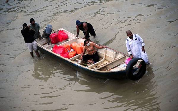 Sebuah bot digunakan untuk membawa mangsa banjir ke kawasan yang lebih selamat selepas kediaman mereka dinaiki air. - Foto Bernama 