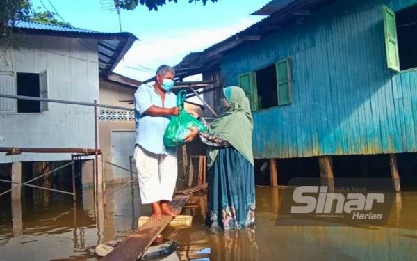 Siti Zailah (kanan) turun padang menyampaikan bantuan banjir kepada penduduk yang terjejas di Kampung Lubok Gong, Rantau Panjang pada Khamis.