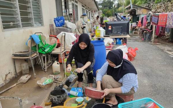 Malaatul (kiri) dibantu ahli keluarganya membantu mengemas kediamannya yang terjejas akibat banjir di Kampung Kebun Bunga, Batu 3, Shah Alam.