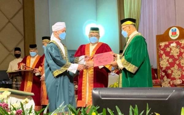 Ahmad (kanan) menyampaikan sijil graduasi kepada pelajar tahfiz yang terlibat.