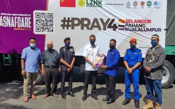 Tengku Sarafudin Badlishah (tengah) menyerahkan beras kepada Zakaria (dua dari kanan) sebagai gimik penyerahan bantuan sebelum menyempurnakan Majlis Pelepasan Misi Bantuan Banjir LZNK ke Selangor, Kuala Lumpur dan Pahang di pekarangan Stadium Darul Aman, pada Khamis.