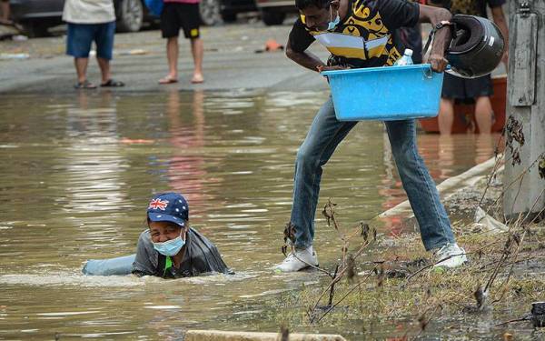 Seorang wanita yang membawa barangan keperluan terjatuh ke dalam air ketika mengharungi banjir termenung di Taman Sri Muda, Shah Alam.