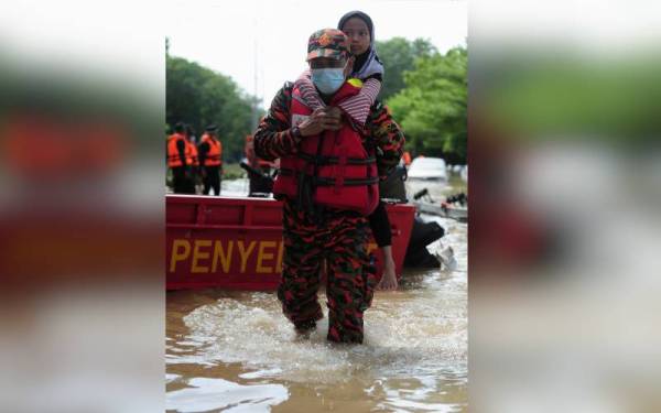 Anggota Jabatan Bomba dan Penyelamat Malaysia (JBPM) membantu mengendong seorang kanak-kanak ketika misi menyelamat mangsa banjir di Taman Seri Muda Seksyen 25. - Foto Bernama