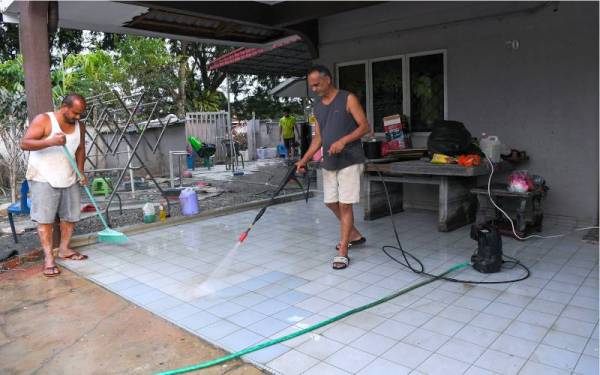 Mangsa banjir K. Mohan,55, (kanan) bersama adiknya K. Kalimuthu,48, (kiri), membersihkan rumah mereka yang ditenggelami air berikutan banjir yang melanda di Taman Seri Muda Seksyen 25 pada 17 Disember lalu ketika tinjauan pada Jumaat. - Foto Bernama 