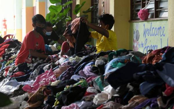 Golongan kanak-kanak yang terjejas akibat banjir memilih baju hasil sumbangan orang ramai yang diagihkan di Pusat Pemindahan Sementara Sekolah Kebangsaan Bukit Piatu pada Jumaat. - Foto Bernama