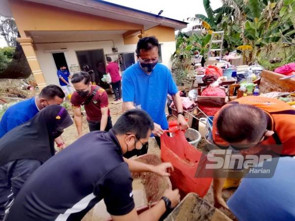 Mohd Salim (tengah) membantu membersihkan rumah mangsa banjir di Kampung Kuala Klawang.