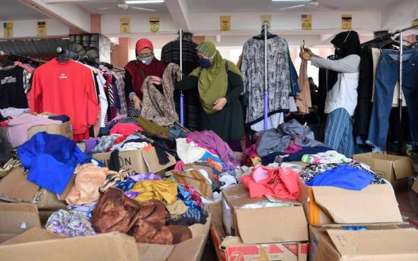 Mangsa banjir memilih pakaian di Pusat Pemindahan Sementara (PPS) Sekolah Kebangsaan Kota Warisan ketika tinjauan. Foto Bernama