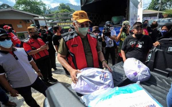 Menteri Komunikasi dan Multimedia Tan Sri Annuar Musa bersama sukarelawan Kementerian Komunikasi dan Multimedia (KKMM) dan Rumah Prihatin mengagihkan bantuan makanan dan barangan keperluan harian kepada mangsa banjir di Kampung Pulau Santap Janda Baik pada Program Prihatin Menteri Komunikasi dan Multimedia hari ini. - Foto Bernama
