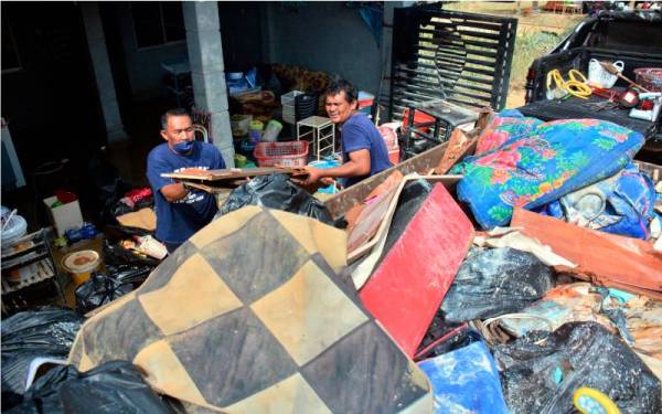 Sukarelawan membantu membersih rumah serta membuang kelengkapan rumah penduduk yang musnah dilanda banjir di Taman Bukit Rangin Aman pada Sabtu. - Foto Bernama 