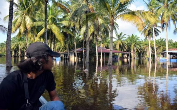 Penduduk setempat Aiman Najmi Adnan meninjau keadaan banjir yang melanda Kampung Semangat pada Sabtu. Foto Bernama
Meskipun cuaca dilihat agak baik sejak lima hari lepas namun keseluruhan kampung itu kini dilanda banjir ekoran limpahan air sungai Pahang yang mengalir turun dari daerah hulu.
