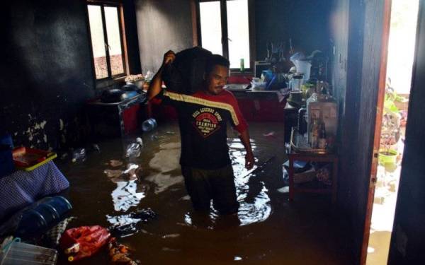 
Penduduk setempat Tengku Aliff Sazali T. Mohd Hashim membawa dokumen penting ketika meninggalkan kediamannya yang dinaiki air di Kampung Semangat.- Foto Bernama
