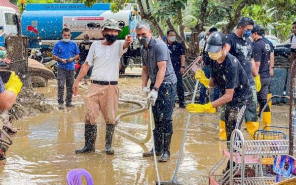 Tengku Zafrul (dua kanan) giat melakukan kerja-kerja pembersihan di kawasan banjir Sungai Lui.