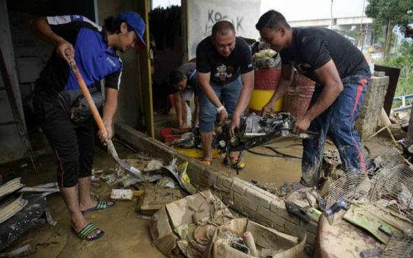 Orang ramai melakukan kerja-kerja pembersihan setelah banjir mulai surut.- Foto Bernama