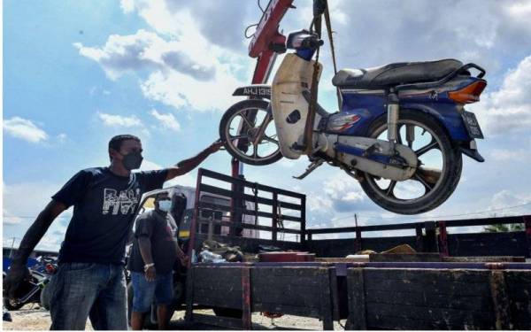  K Maniam Rajoo, 46, memastikan motosikal yang terjejas dibawa dalam keadaan baik sebelum dihantar ke pusat servis susulan kejadian banjir baru-baru ini.- Foto Bernama
